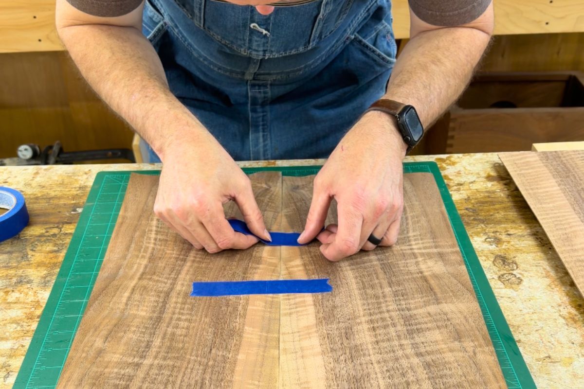 Taping two bookmatched veneer halves together to prepare a handcrafted cajon faceplate in the Kopf Percussion workshop