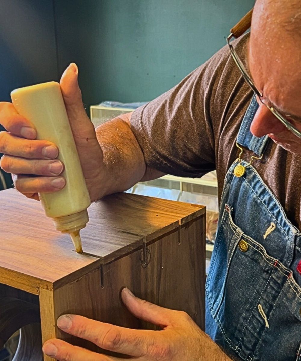 Workshop process shot of sanding and shaping a handcrafted walnut Cajon body.