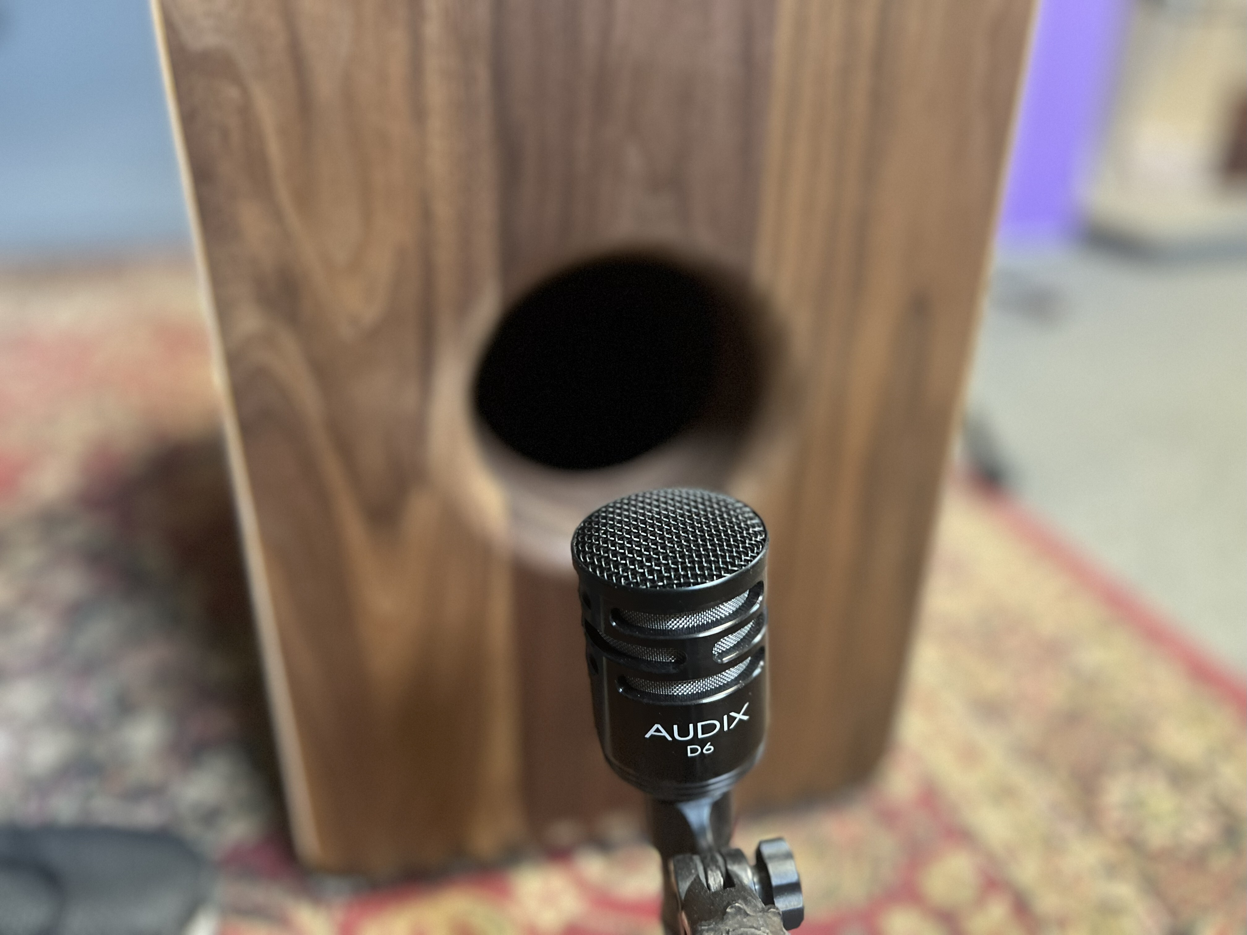 Rear Microphone Placement at Sound Port – Kopf Percussion A close-up photo of a Kopf Percussion bass cajon with a microphone positioned near the sound port on the side panel. This setup captures low-end depth and body resonance, ideal for blending with a front mic to achieve a balanced live or studio tone.