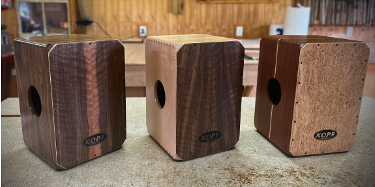 Lineup of handcrafted cajons in different woods — birch, maple, walnut, cherry, and oak