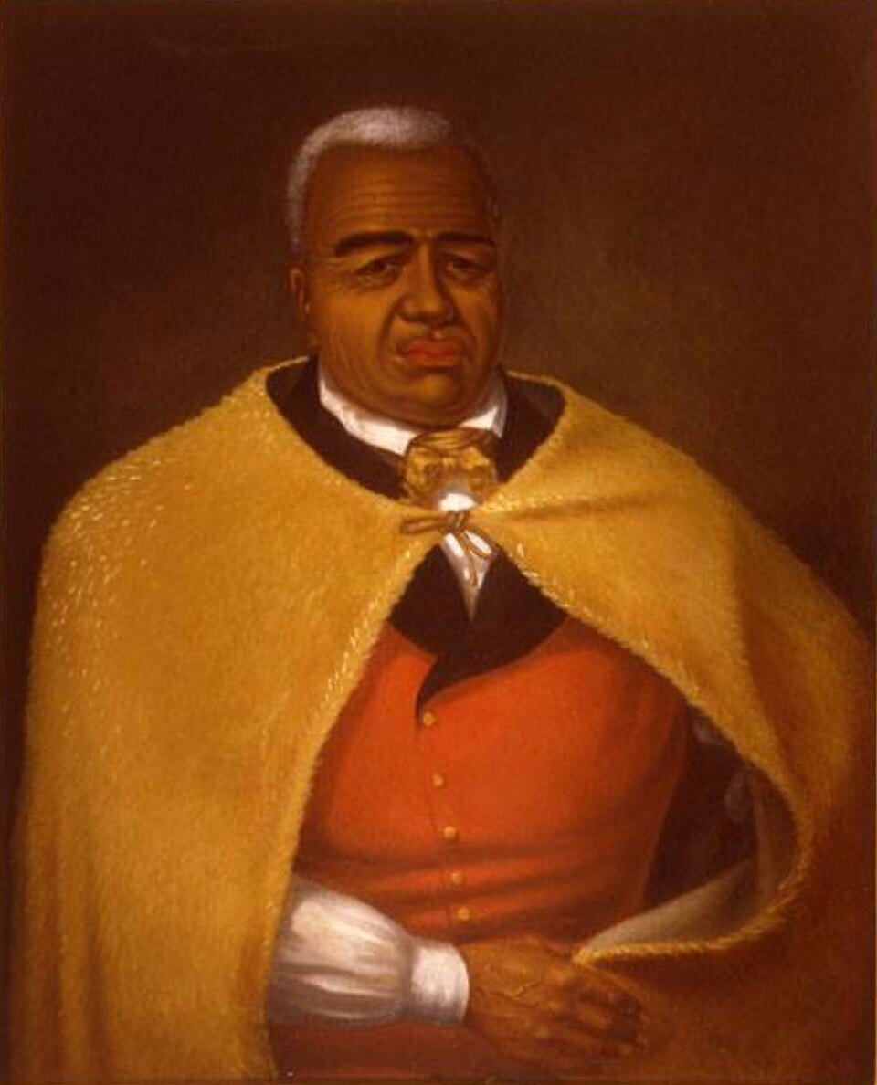 Public-domain 19th-century painting of King Kamehameha I, created by artist James Gay Sawkins. The image depicts the Hawaiian monarch wearing his royal feather cloak and helmet, representing the era when koa wood was reserved for Hawaiian royalty.