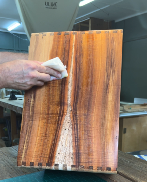 Studio photo of Stephen Head at Kopf Percussion applying naptha to a solid koa Cajon body to reveal the wood’s natural figure and grain pattern. The image shows the depth, color variation, and craftsmanship that make koa an exceptional tonewood for percussion instruments.